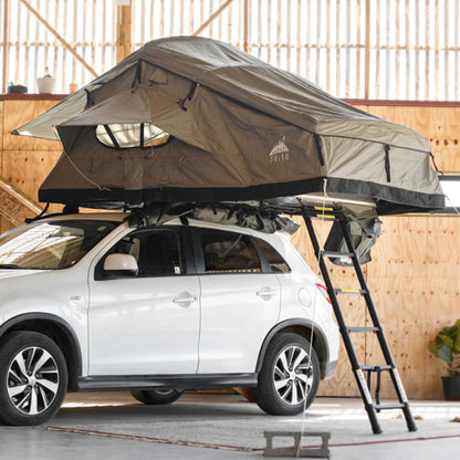 Tribu Carpa de Techo rooftop tent mounted on white SUV with ladder extended indoors